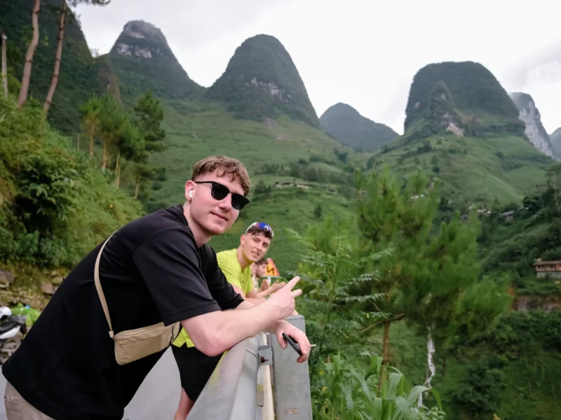 Breathtaking view of tourists posing at Ma Pi Leng Pass, a must-see on the Ha Giang Loop Motorbike Tour 3 Days 2 Nights